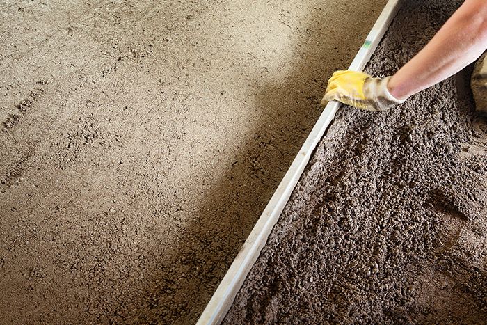 Person verteilt Schüttung mit Richtlatte